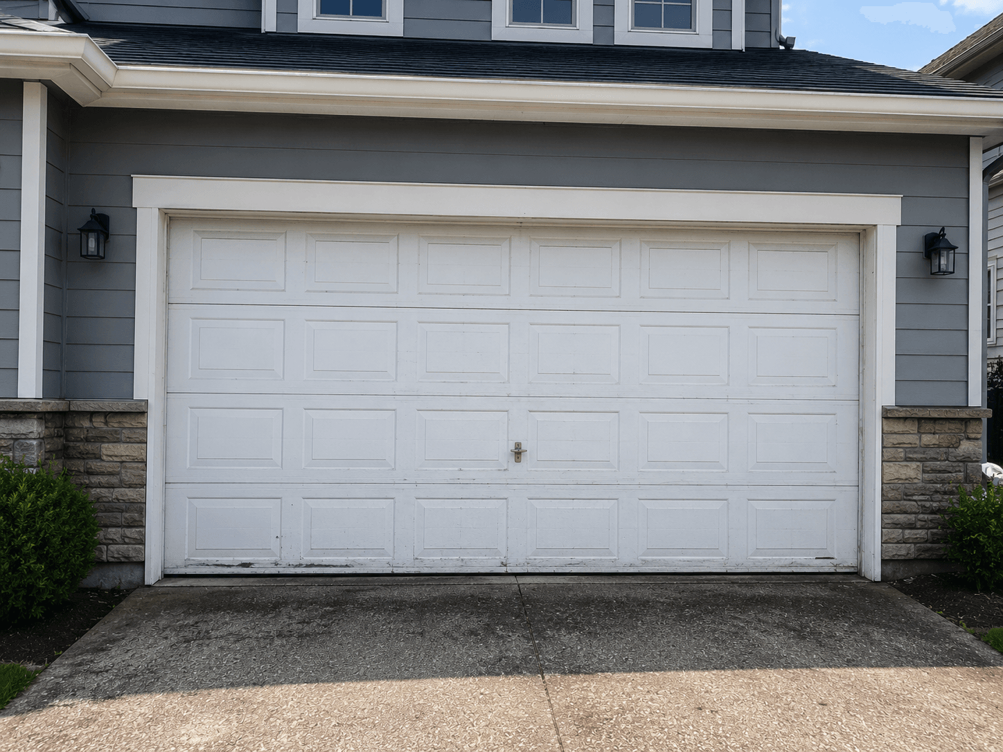 Suburban home with worn and outdated garage door before replacement