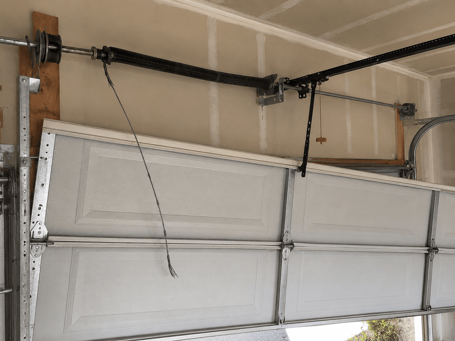 Before emergency cable repair showing a snapped garage door lift cable causing an uneven garage door in Bonney Lake