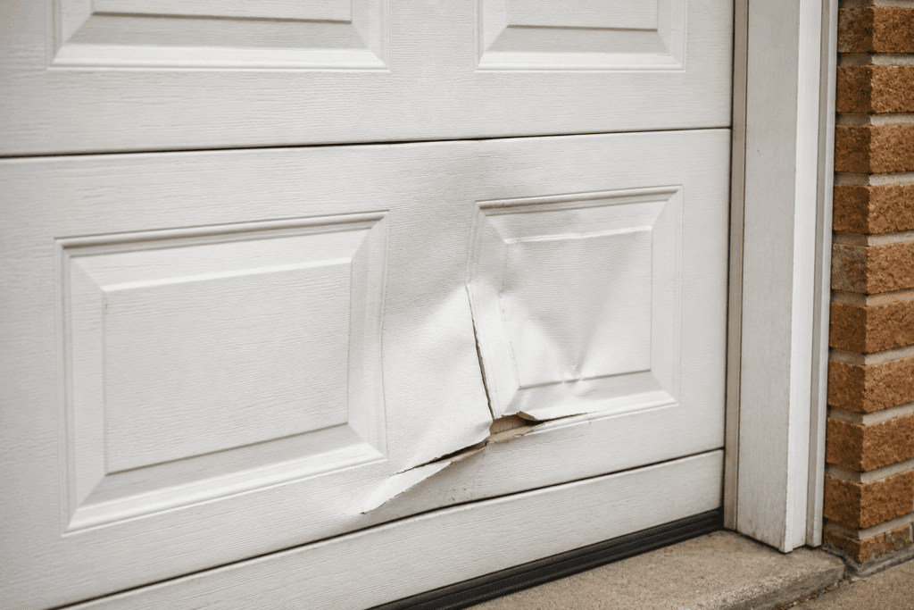 Garage door panel repair showing a dented lower garage door panel with impact damage on a residential garage door