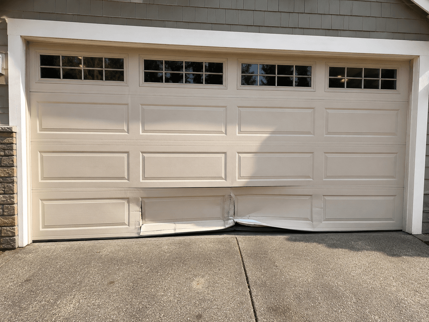 Before garage door panel repair showing a damaged lower panel on a residential garage door near Prairie Ridge
