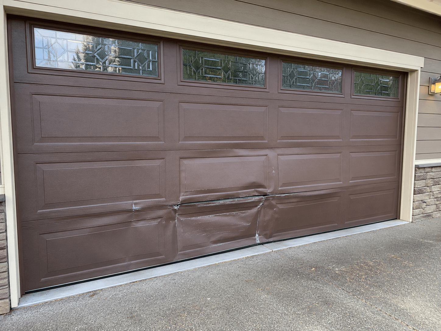 Before garage door panel repair showing impact damage to lower garage door panels at a home in East Tacoma